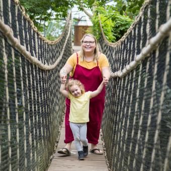 Woman and daughter walking across the bride in the Rainforest